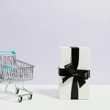 Minimalist shopping concept with cart and gift box tied with black ribbon.