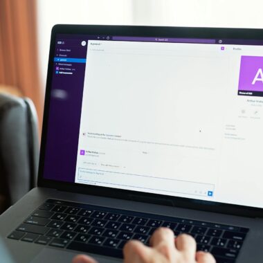 Person using a laptop with an online communication platform, showcasing modern work tech.